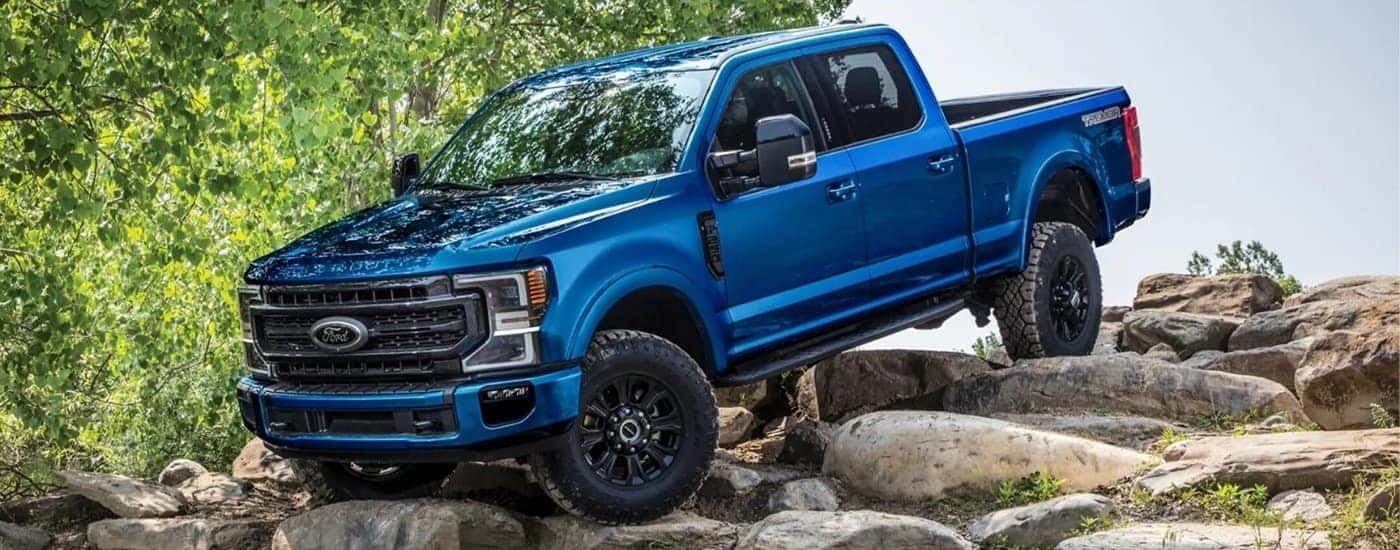 A blue 2022 Ford F-350 Super Duty Tremor is shown driving down a rock pile after visiting a Colorado Ford Super Duty dealer.