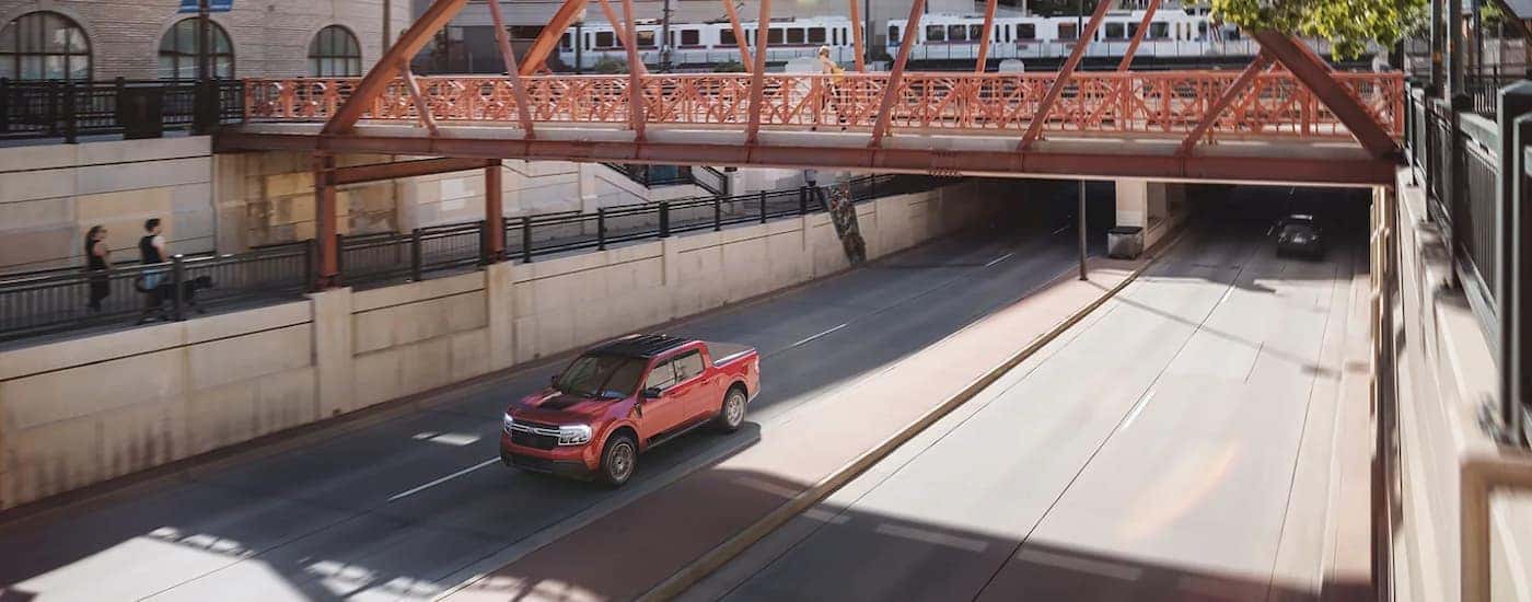 Red 2022 Ford Maverick driving under a bridge