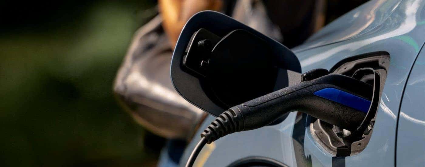 A close up shows a blue 2023 Ford Escape Hybrid charging.