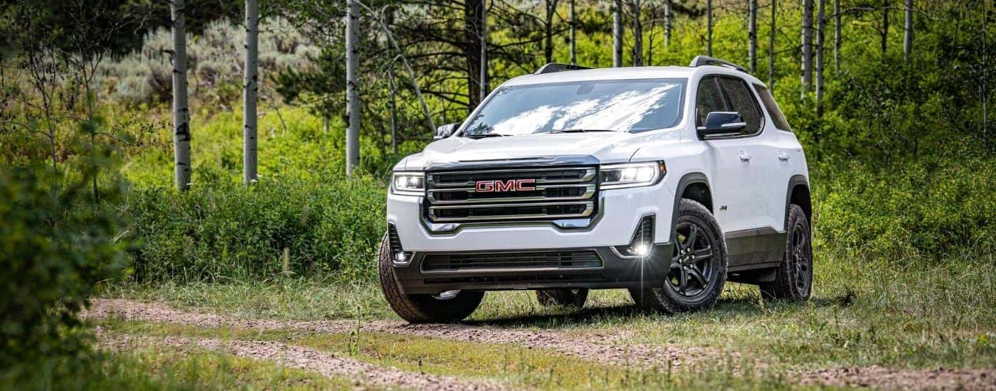 A white 2020 GMC Acadia AT4 is shown from the front at an angle while off-road after leaving a used GMC dealer.