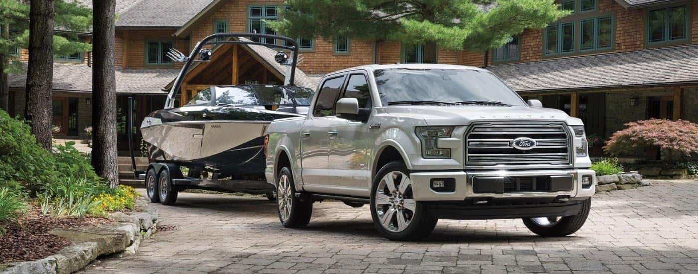 A white 2016 Ford F-150 Limited is shown towing a boat on a trailer.