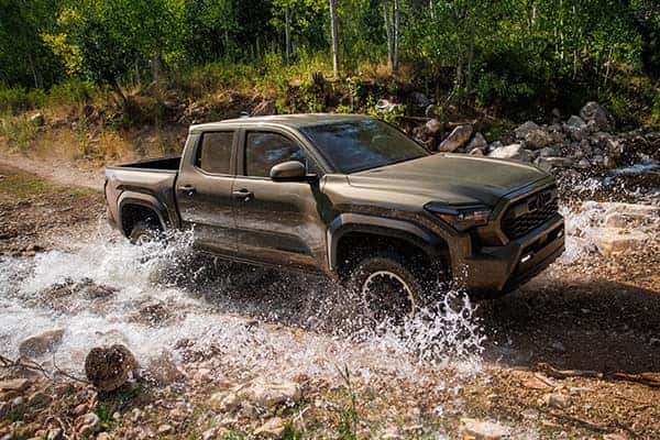 a brand new toyota tacoma driving through some water