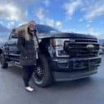customer posting in front of new black truck